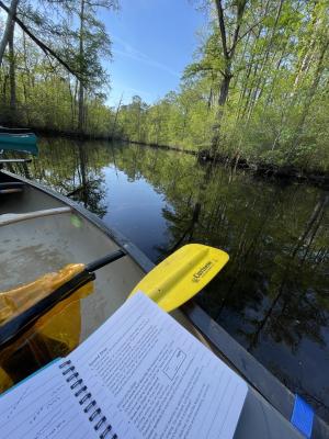 the yellow paddle from a canoe sits on the edge of a boat on a dark river