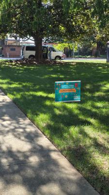 grassy area with large oak trees and decorative sign 