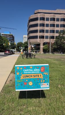 grassy area with picnic tables and decorative sign 
