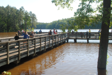 Youth gather on a lake pier for fishing