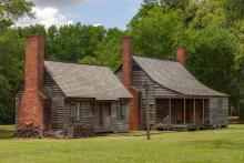 A pair of cabins with brick chimneys and covered porch