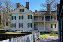 Side view of a two-story white clapboard antebellum house featuring a two-story porch