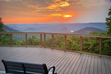 An empty black bench on an empty deck overlooks Morrow Mountain at Sunrise