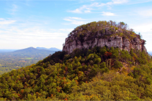 Pilot Mountain's unique geologic knob rises above the piedmont valley, with the Blue Ridge Mountain Range in the background