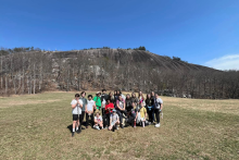 A field trip group stands in the foreground of a large smooth mountain range