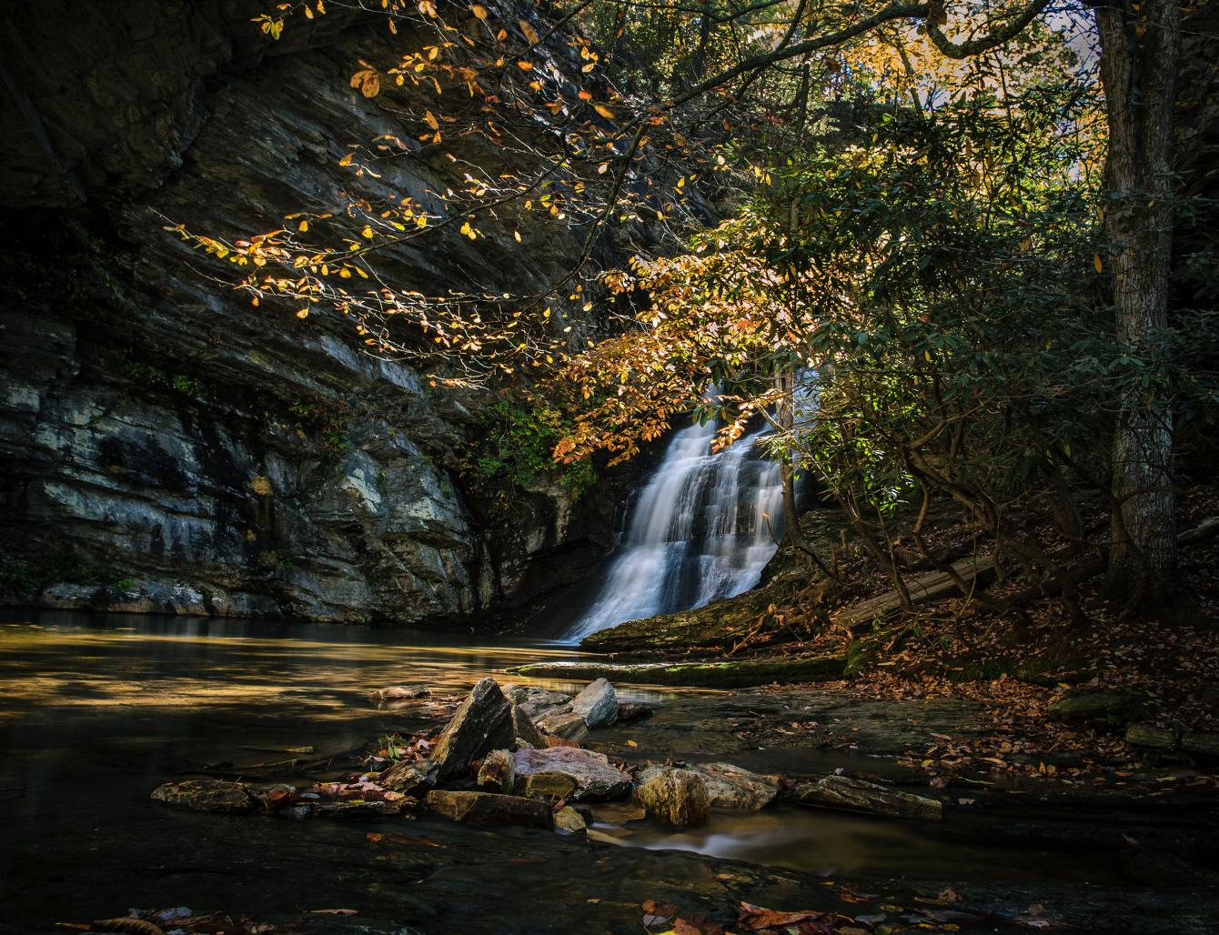 a waterfall flows over quartzite rock into a shallow pool at Hanging Rock State Park