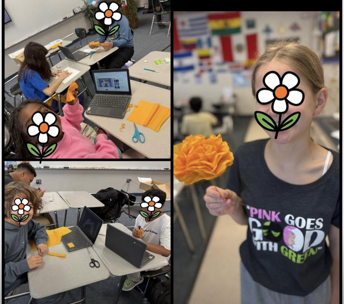 Students hold up paper marigolds they made.