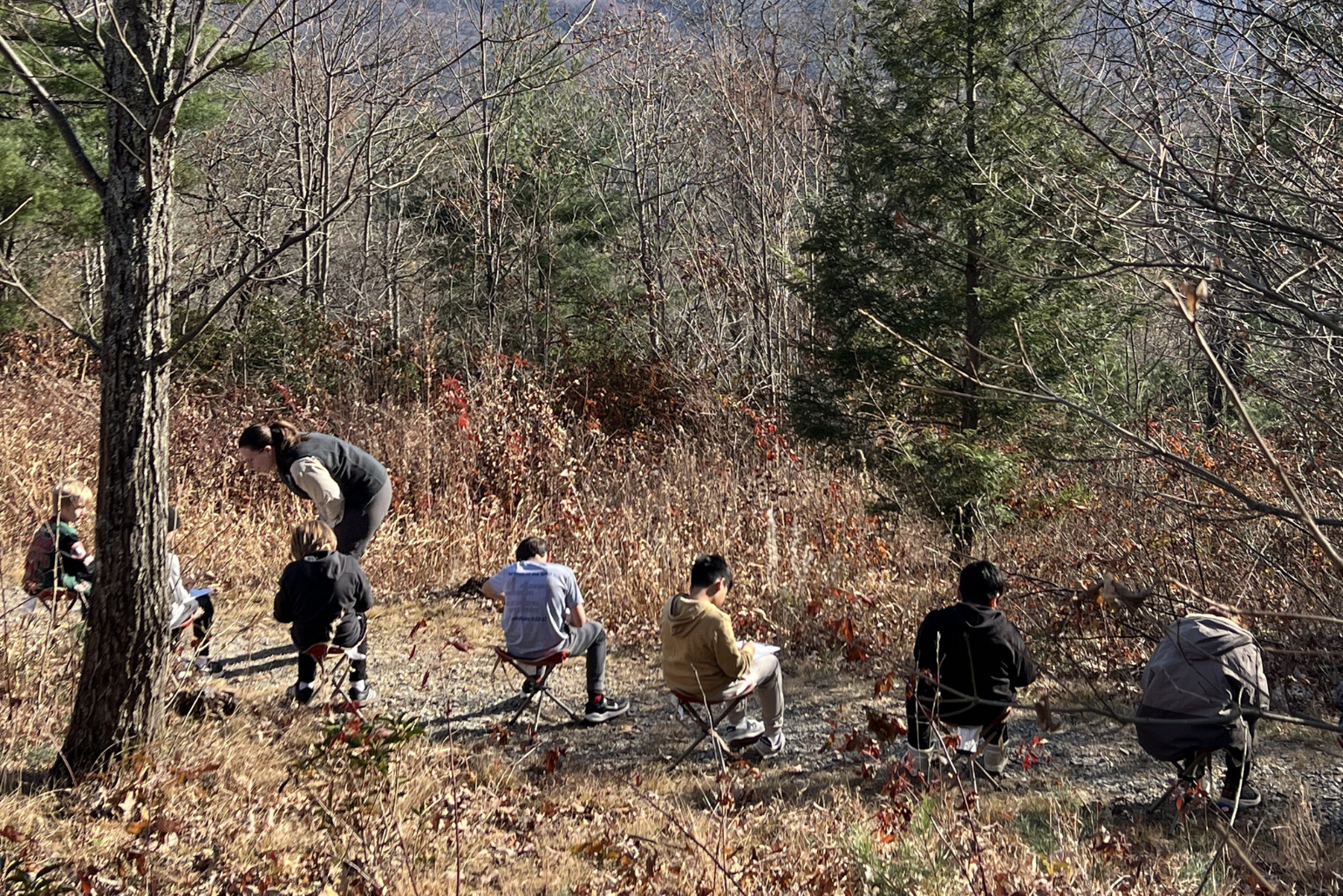 Students sit apart at a lookout over the mountains and journal.