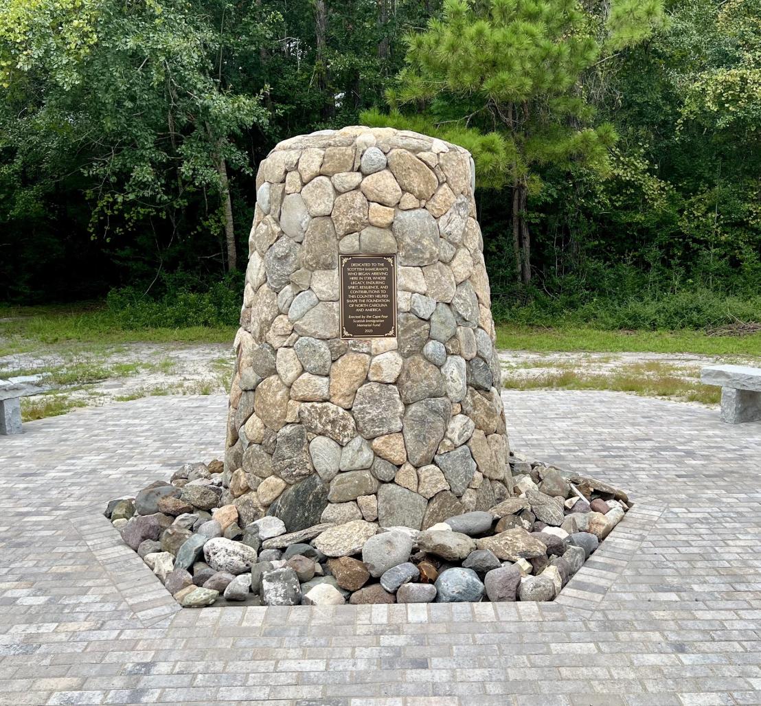 A stone memorial with a bronze plaque on it memorializing Scottish Immigrants