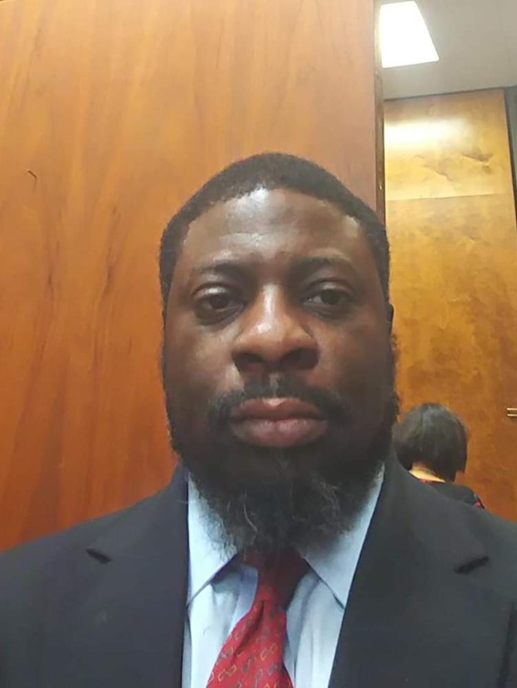 An African American man in a suit looks at the camera