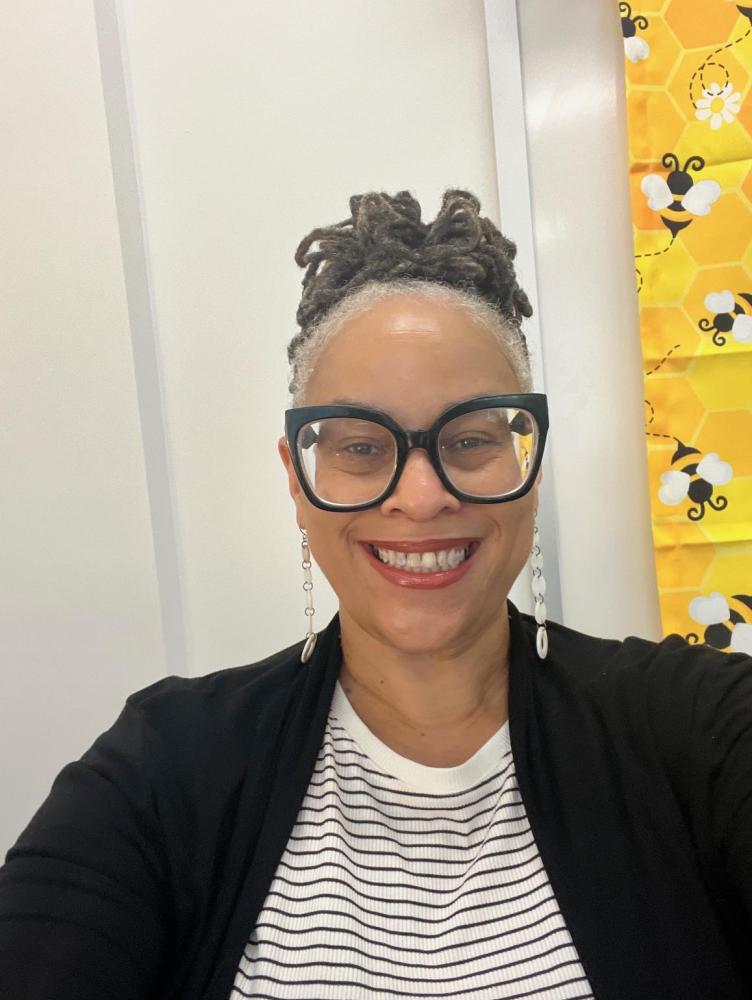 an African American woman with black hair and a black and white shirt smiles at the camera