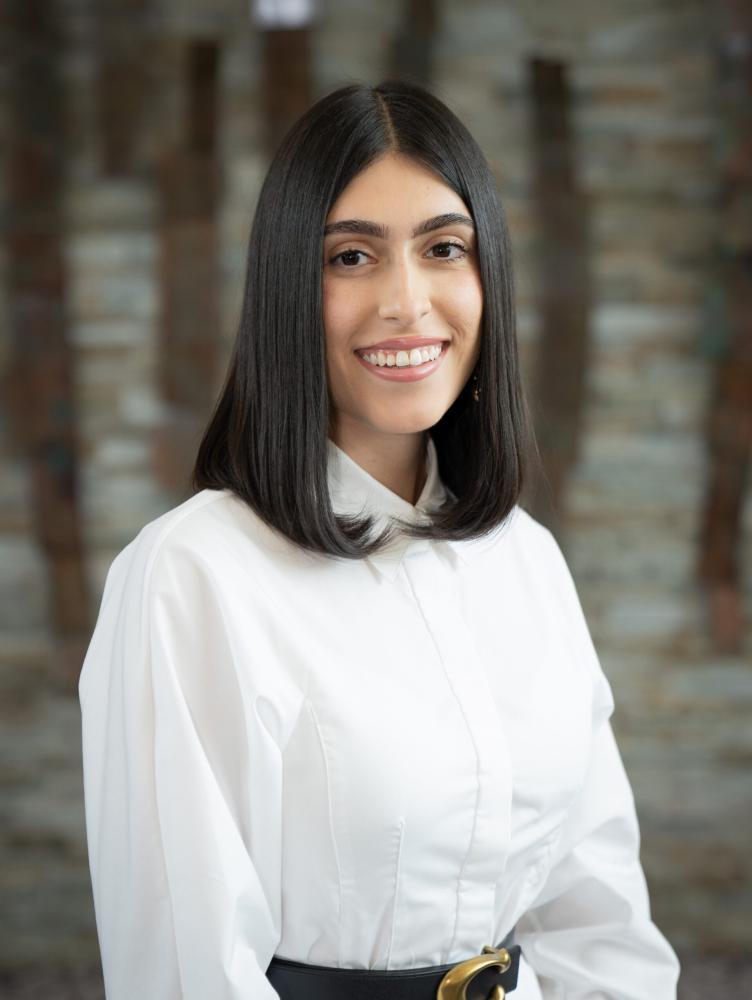 a woman with dark hair and a white button down shirt smiles at the camera