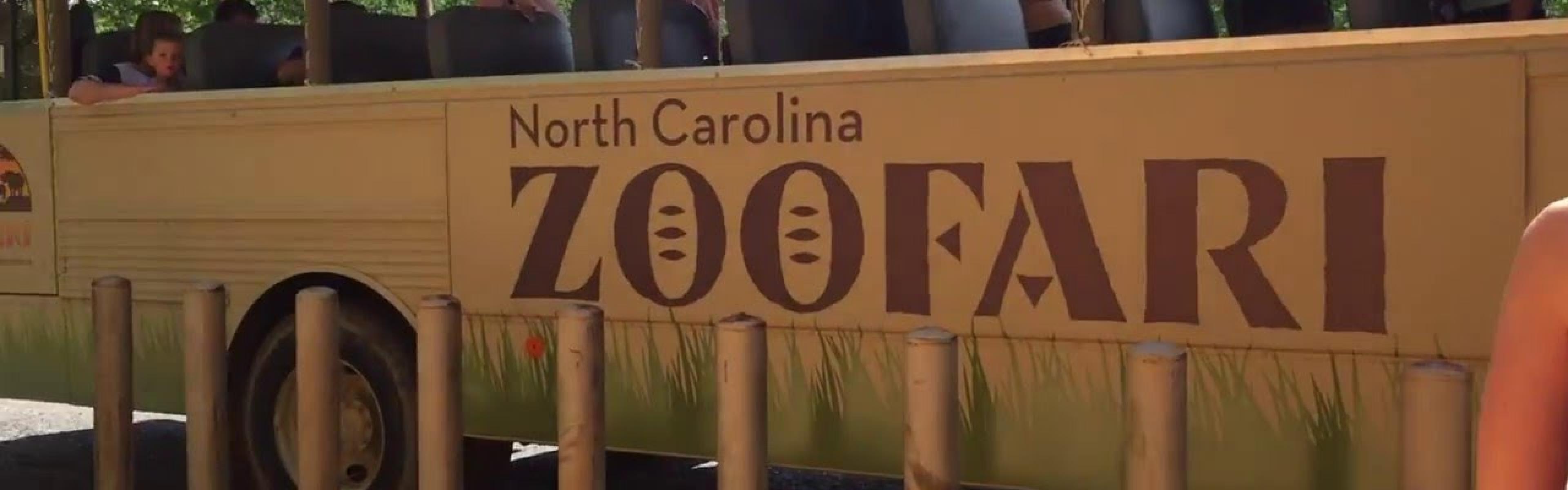 A bus marked "North Carolina Zoofari" with people on it.