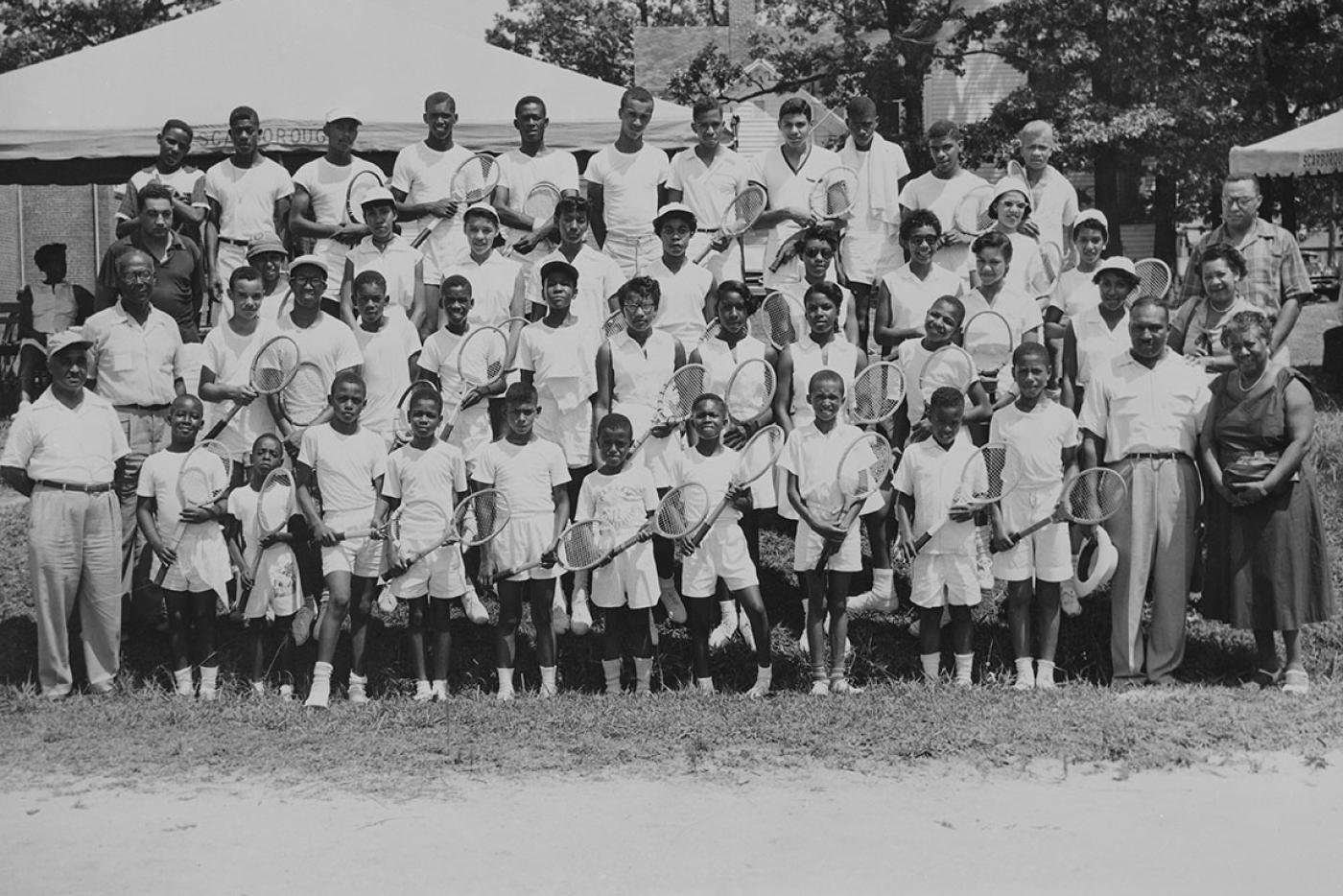 A crowd of people wearing tennis uniforms and holding tennis rackets.