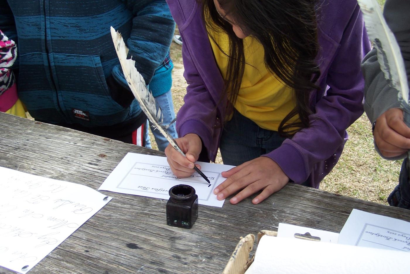 A person signing paper with a quill pen.