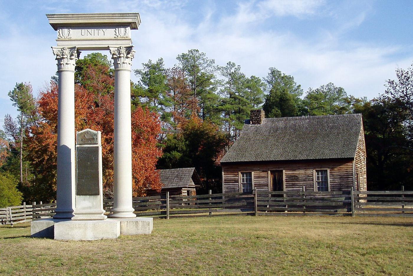 Two pillars with the word "Unity" on top of them. Cabins can be seen next to this monument.
