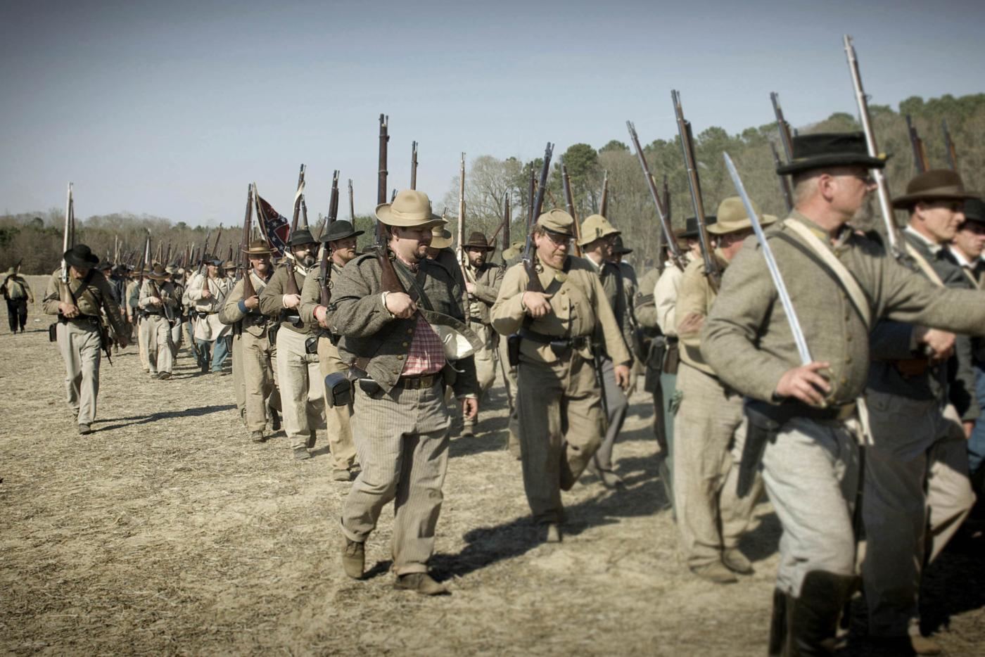 A group of historical interpreters dressed as Civil War soldiers marching in a line.