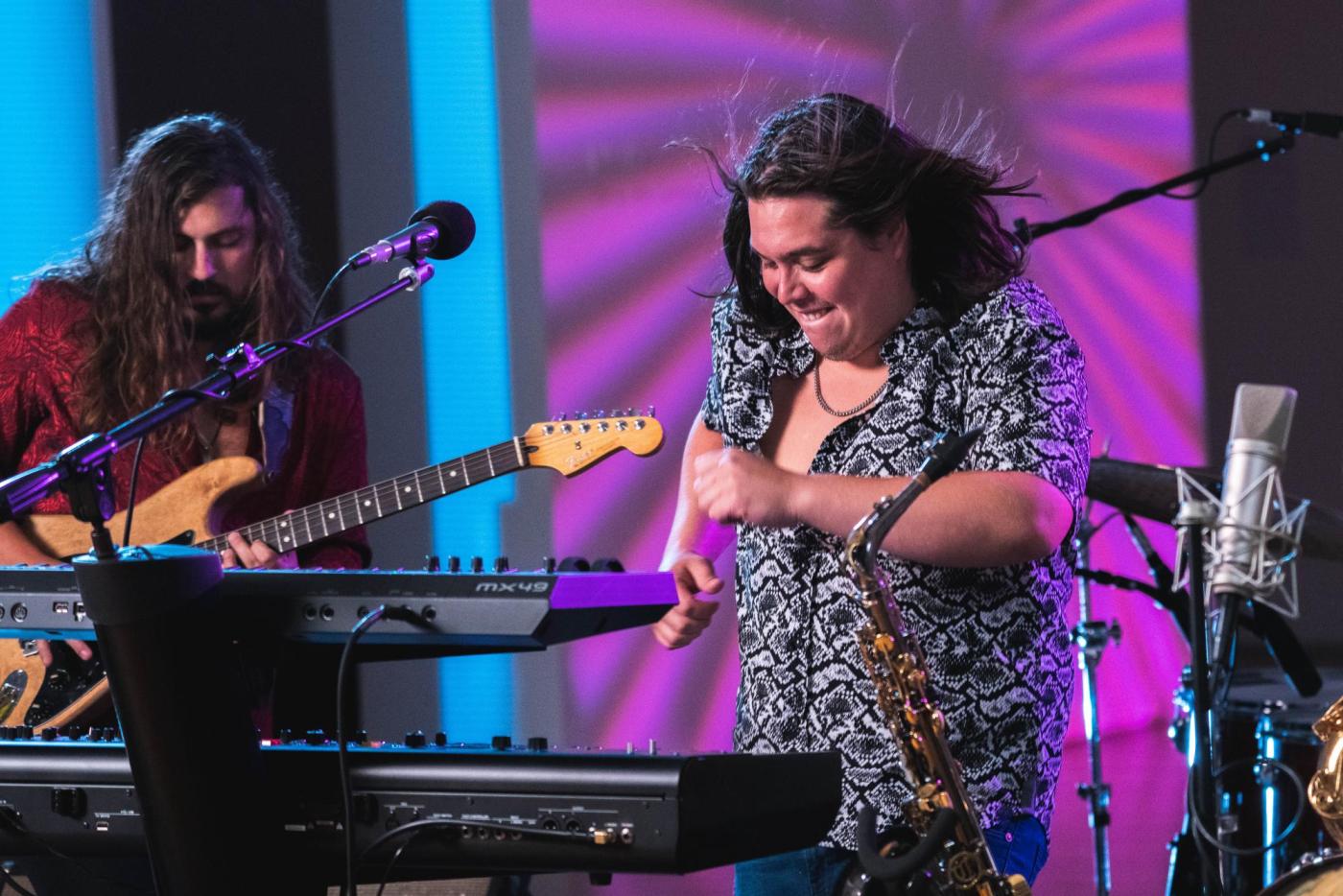 Two band members of Tumbao on stage performing music.