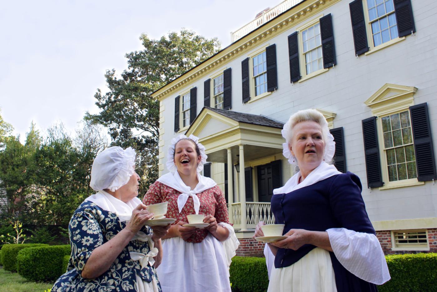 Three historical interpreters enjoying cups of tea outside of Tryon Palace.