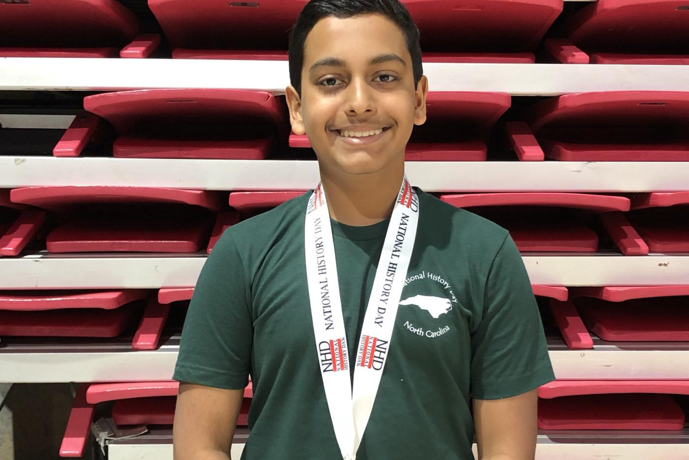 A student smiling with a medal around his neck.