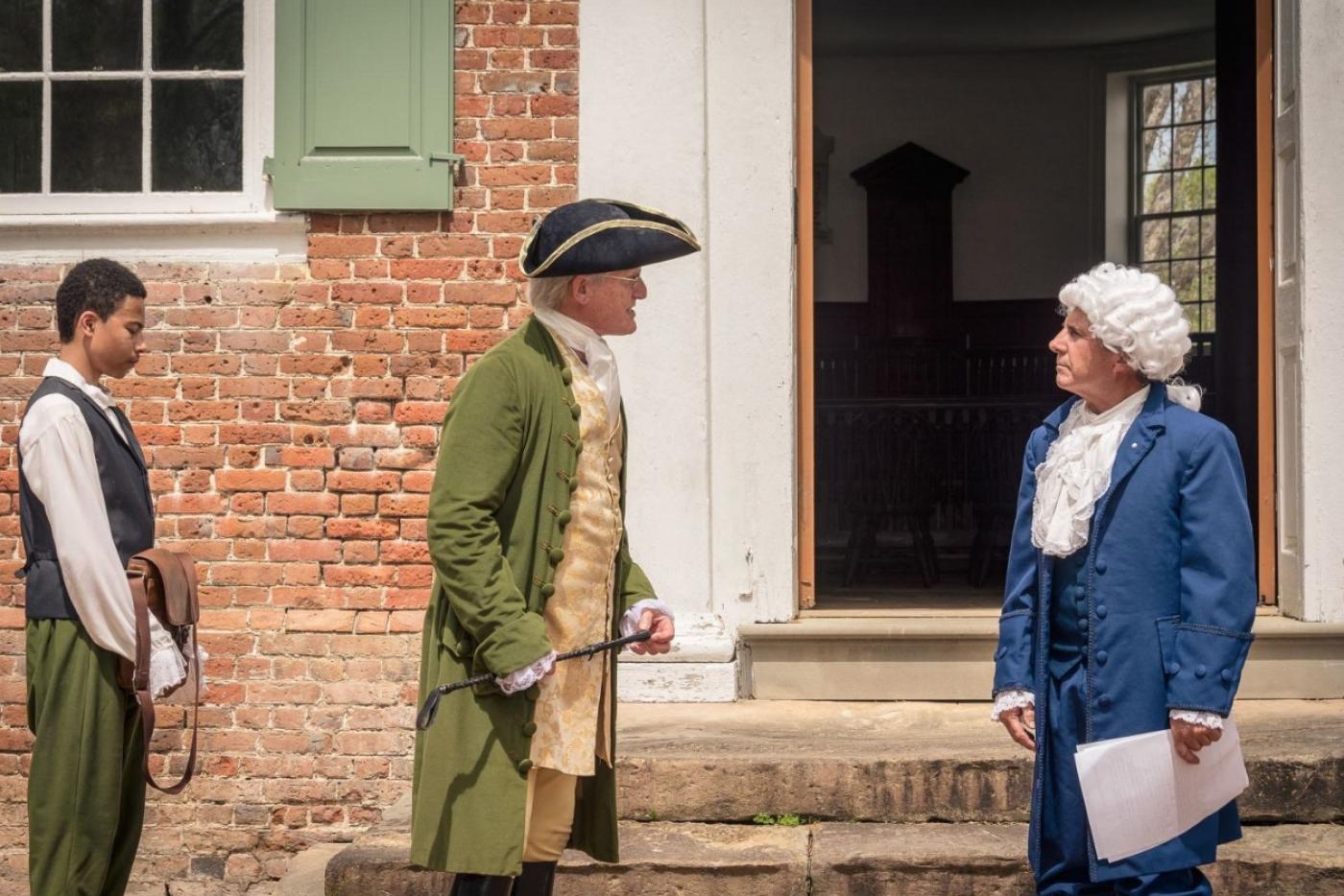 Historical interpreters speaking outside of a building.