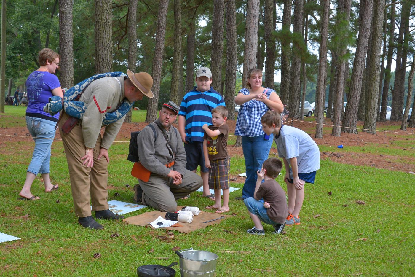 A historical interpreter dressed as a civil war soldier, speaking with members of the public.
