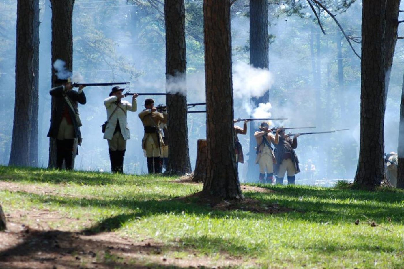 Historical interpreters firing muskets.