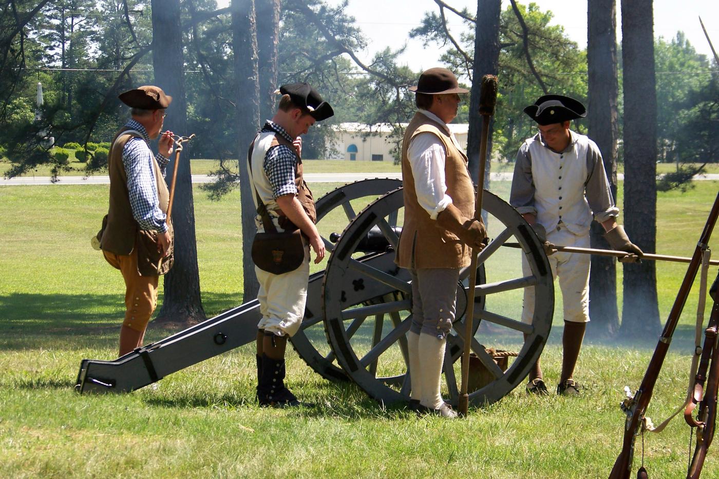 Historical reenactors prepare to fire a cannon