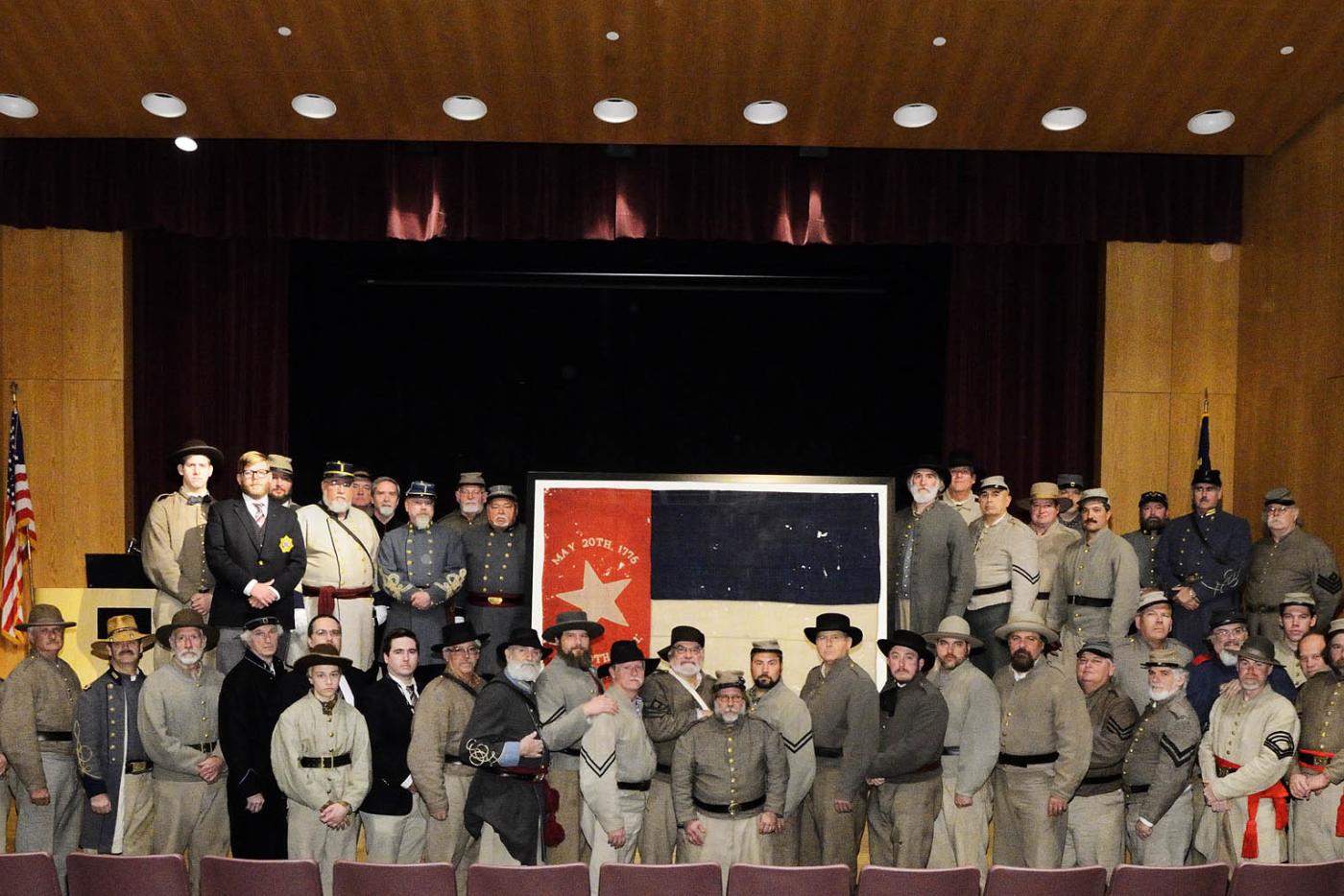 Historic Interpreters dressed as Civil War soldiers surrounding a early version of North Carolina's flag.