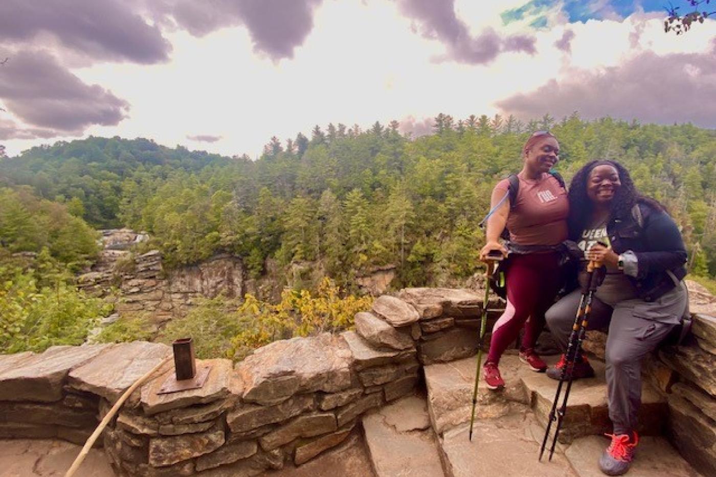 Two people in front of a lush mountain view.