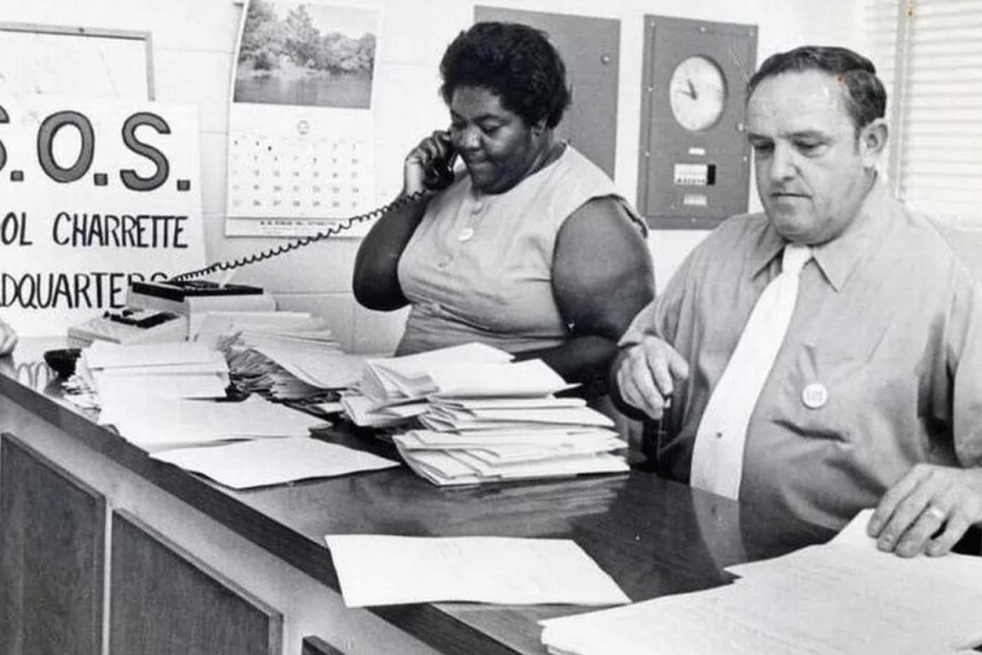 Activist Ann Atwater on the phone, next to a man filling out papers.