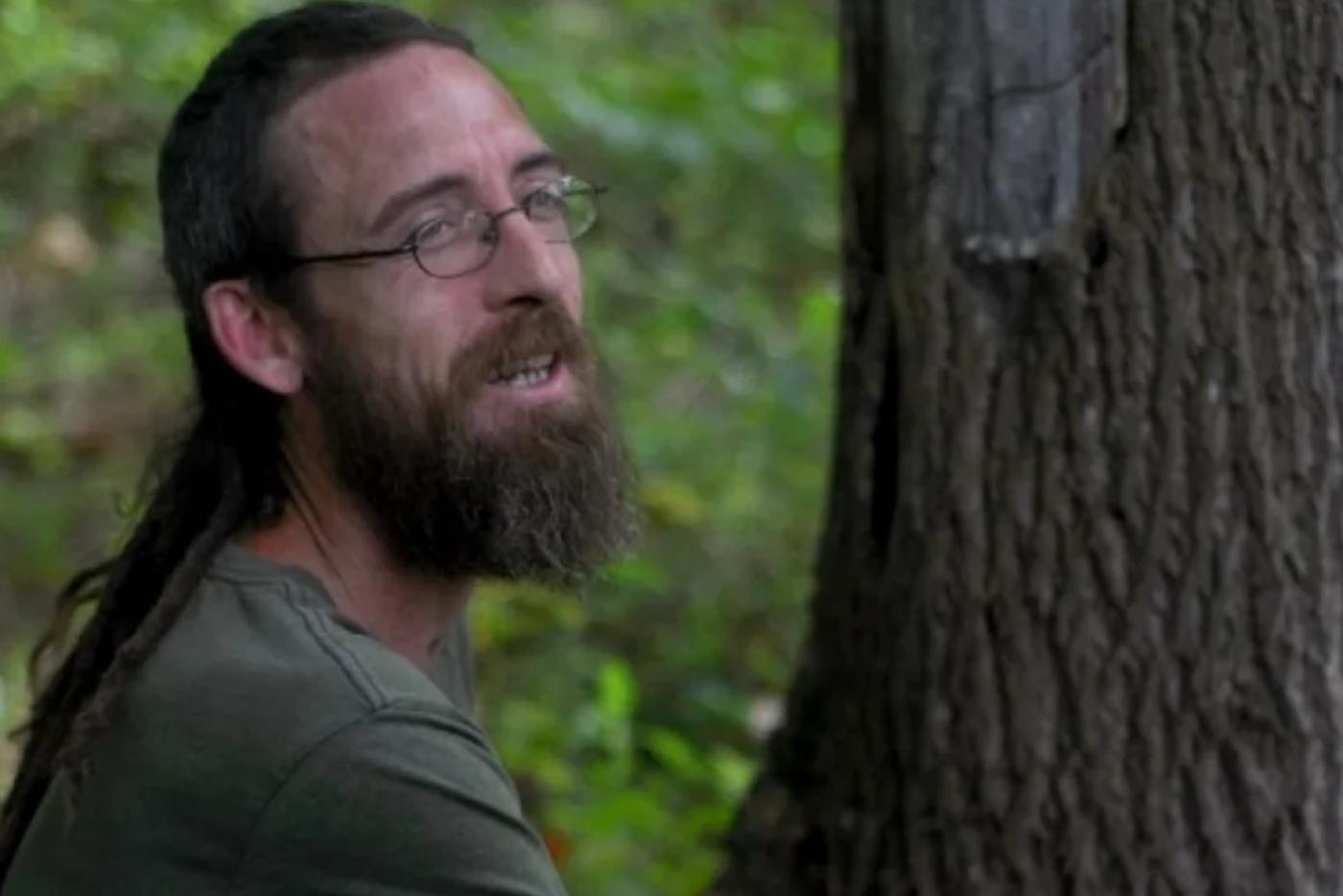 Alex Meander smiling next to a tree.
