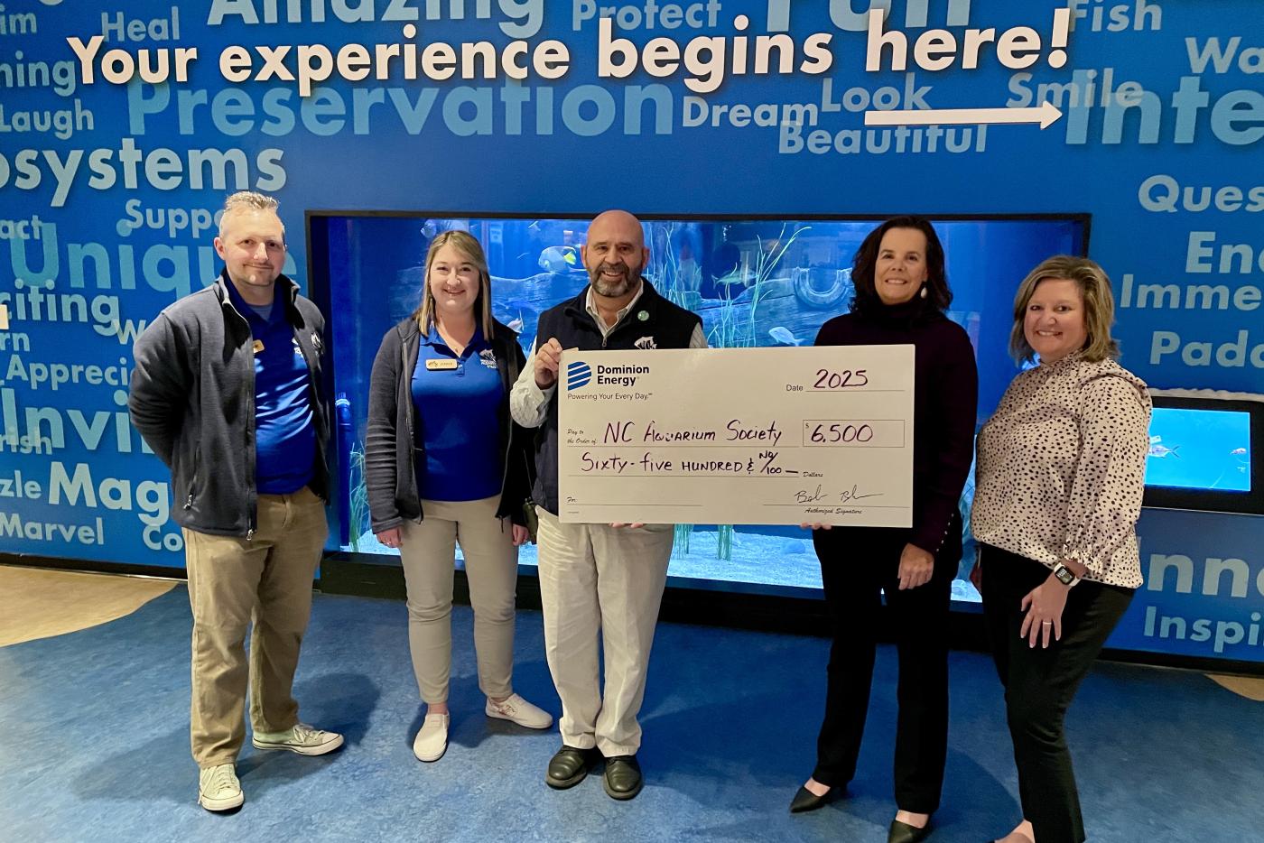 Larry Warner, director of the N.C. Aquarium on Roanoke Island, with exhibits curator Adam Harris and outreach coordinator Jenna Mercier, accepts a check for $6,500 from Winnie Wade and Amy Bunch of Dominion Energy.
