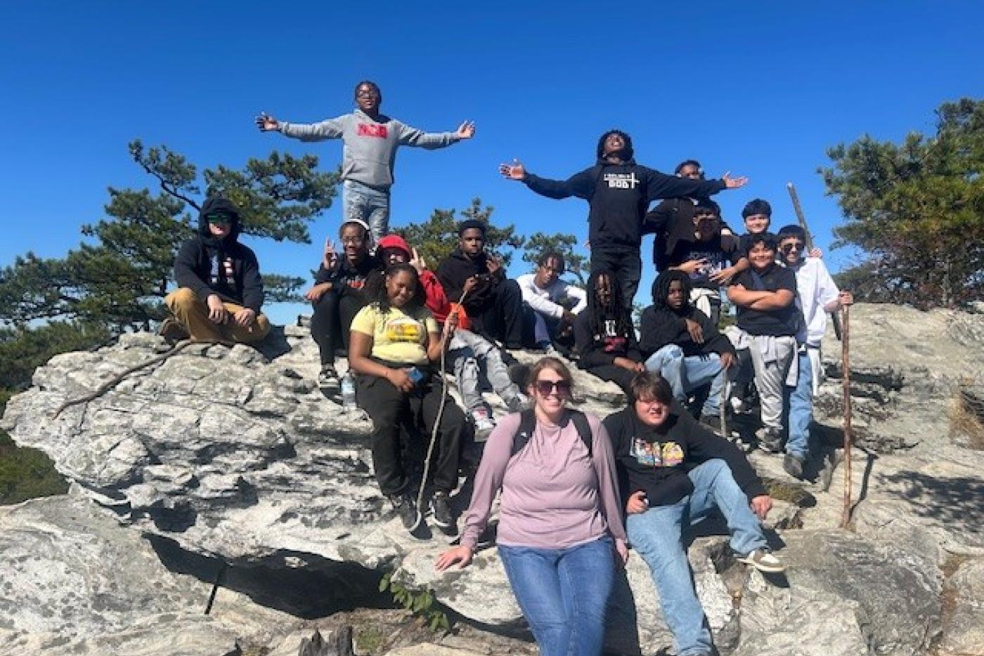 Students and their teacher stand on top of a mountain overlook.