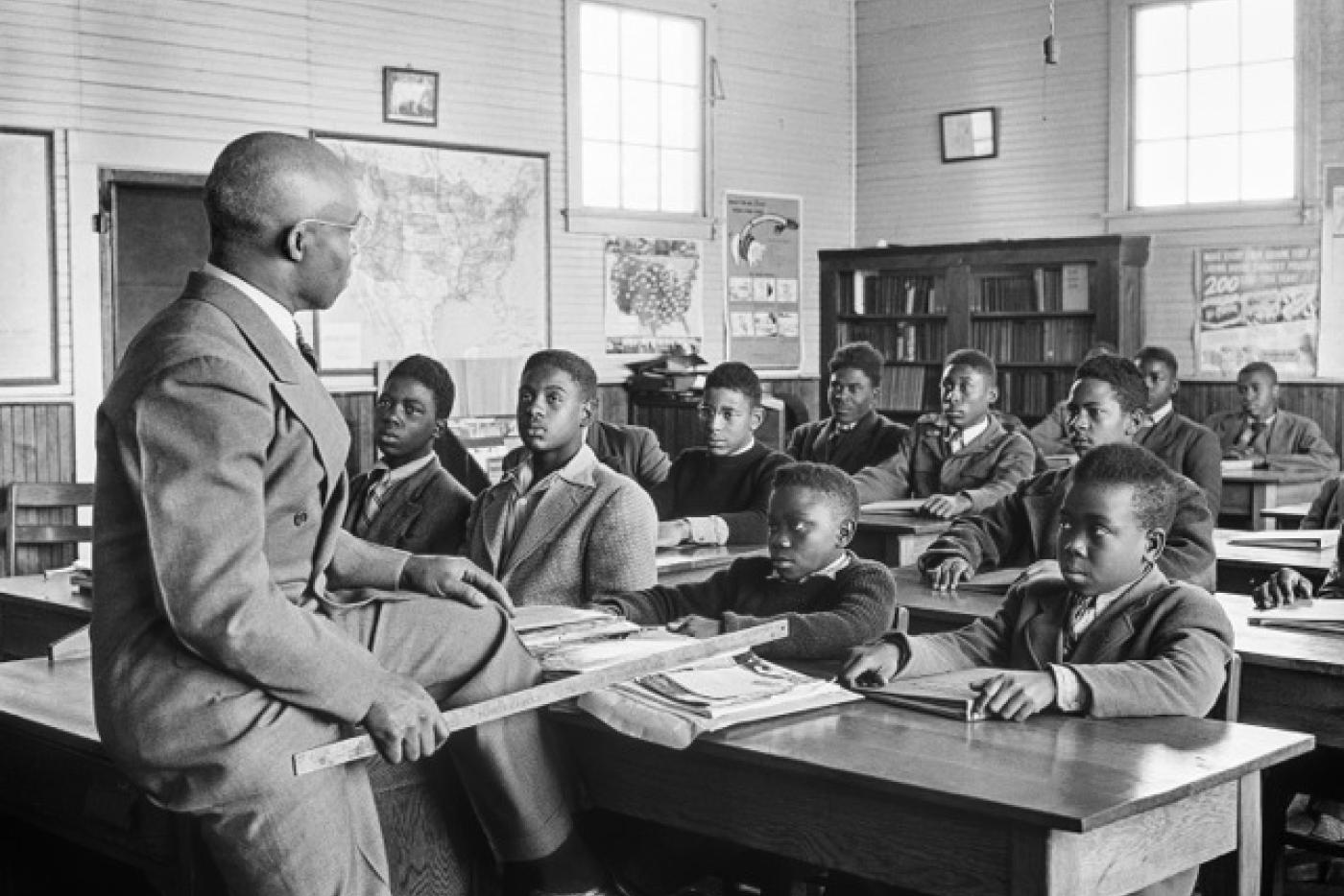 A black and white photo of a teacher talking to a room full of students.