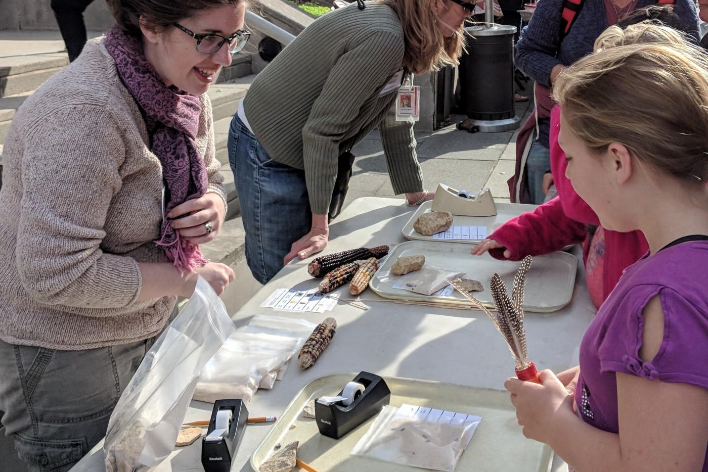 Adults explaining archaeological artifacts to children.