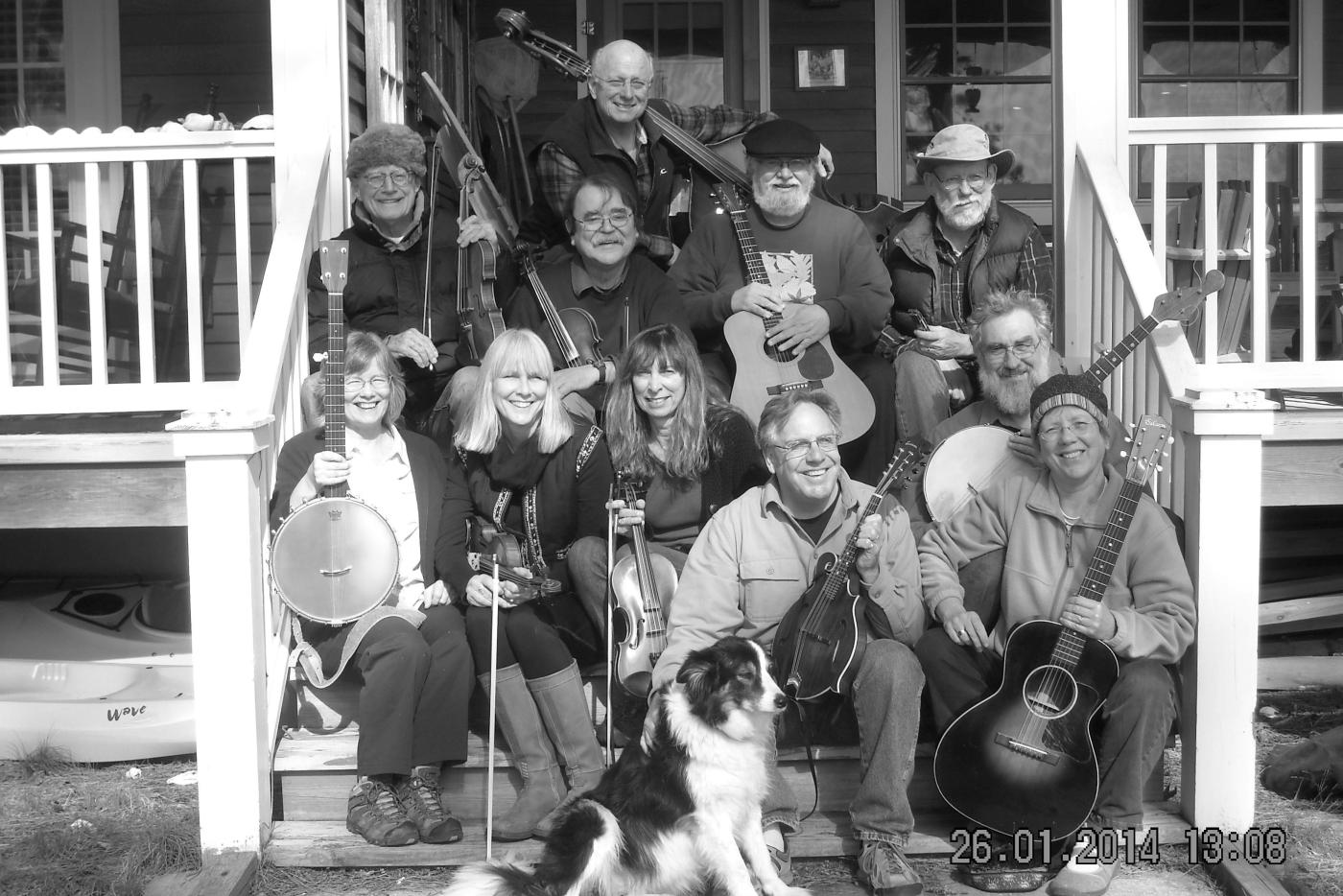 A black and white photo of musicians on a porch with a dog.