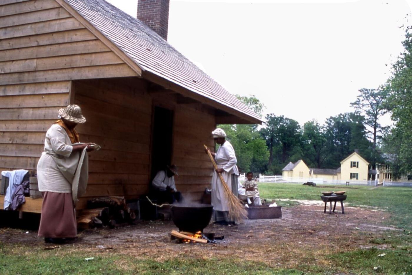 Historical interpreters outside of a cabin at Somerset Place.