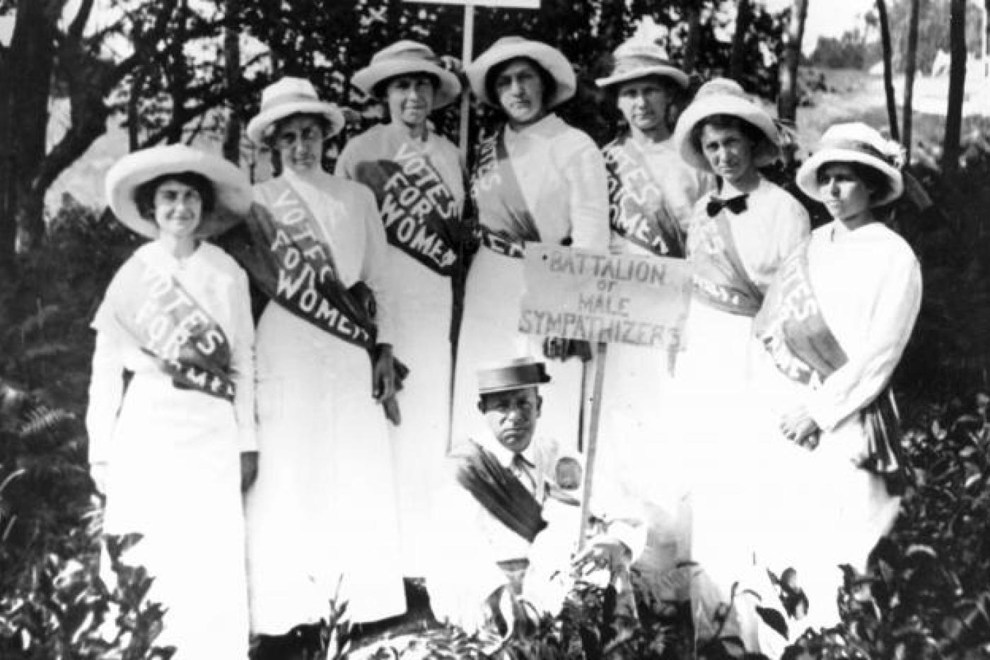 Women carrying signs protesting for women's suffrage.