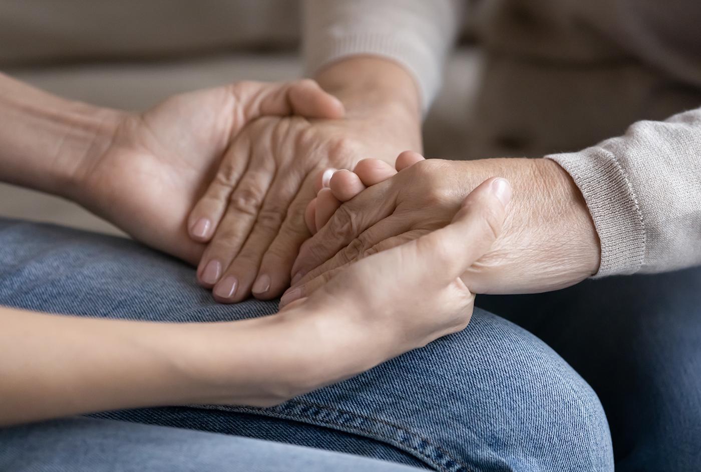 Two people hold hands in comfort.