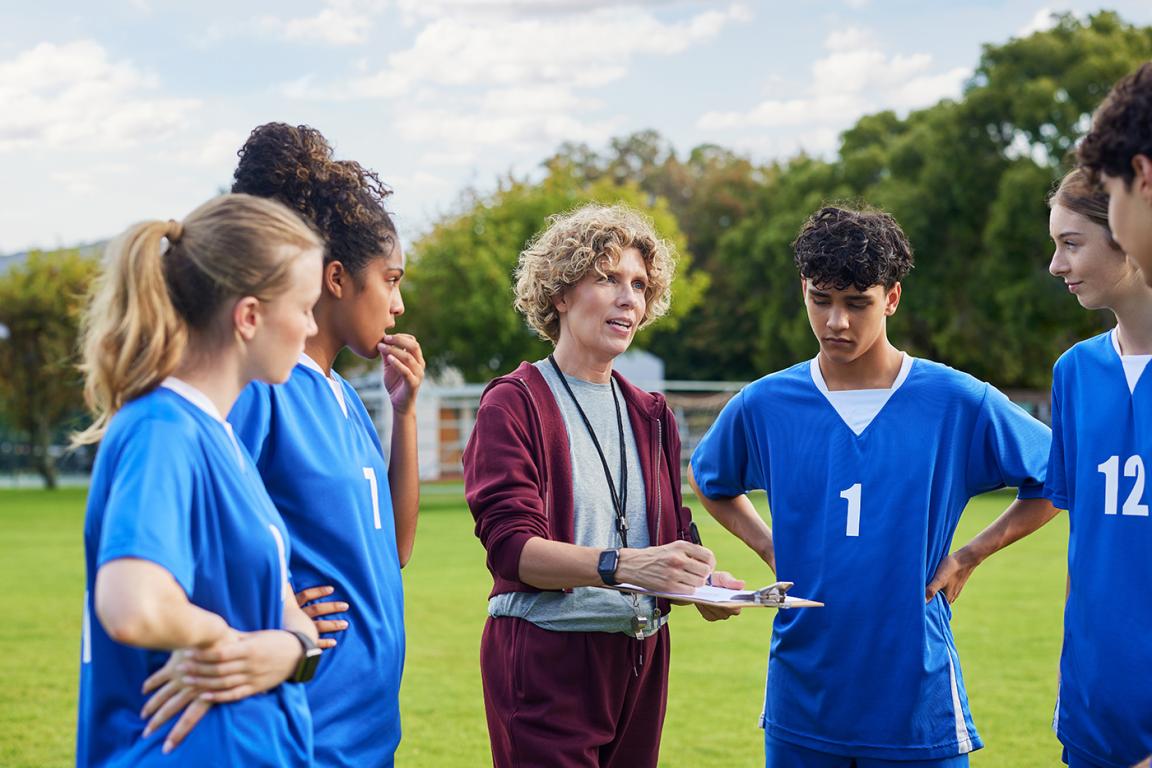 A coach shares strategy with players during a sports practice session.