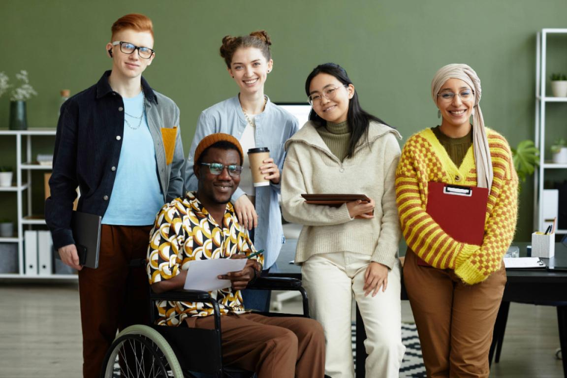 A diverse group of people poses for a photo in an office setting.