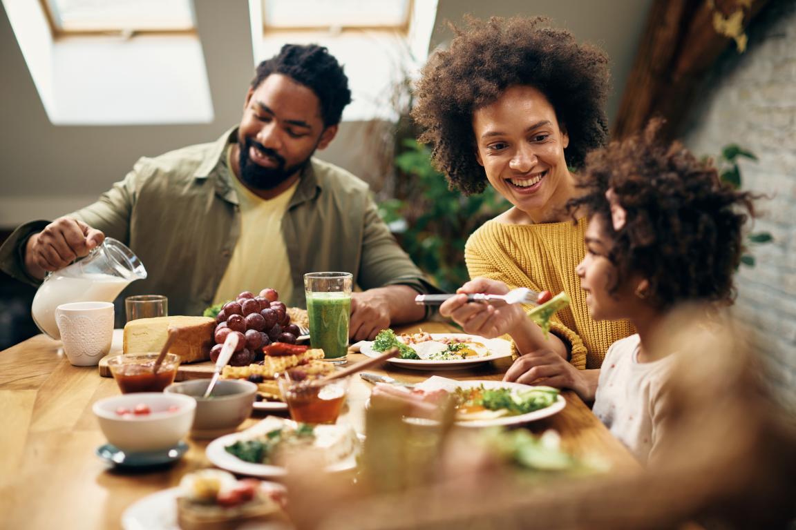 Family of three with a man, woman, and girl child enjoying a healthy meal at a table