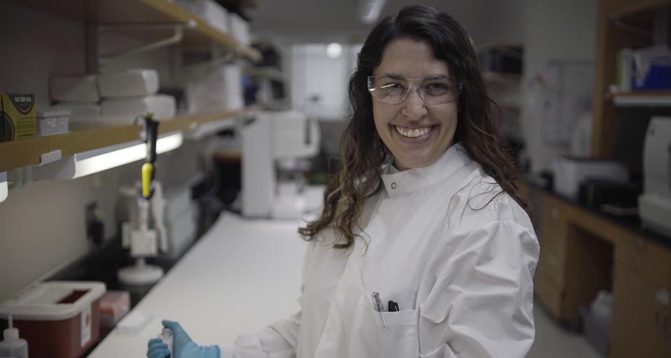 Cecily LaPradd wears protective eye gear and a lab coat while working in the Newborn Screening Lab.