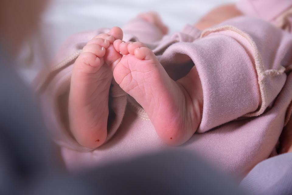 A baby's feet, with dots of blood on each heel from newborn screening tests.