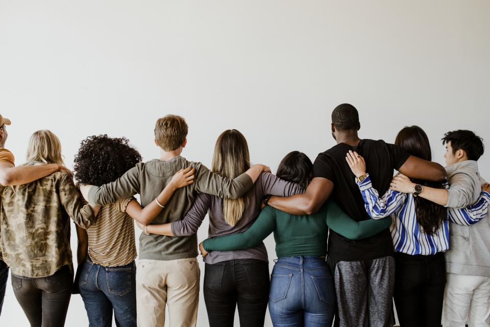 A diverse group of young people hugging in a line.
