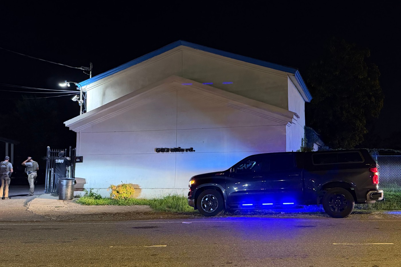 White brick building with law enforcement truck with blue lights activated on
