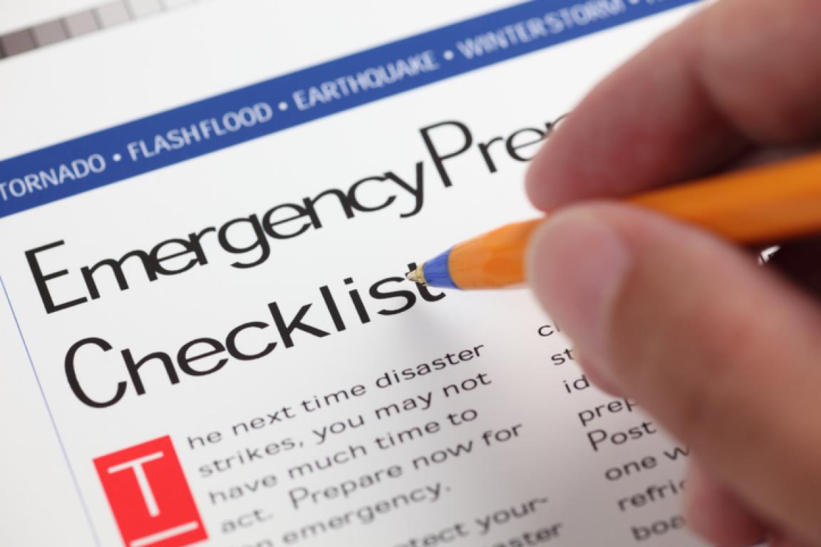 A hand holding a pen over a paper that reads "Emergency preparedness checklist."