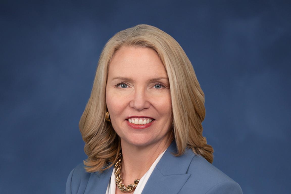 Profile photo of Caroline Valand in a white blouse with a blue blazer on a blue background.