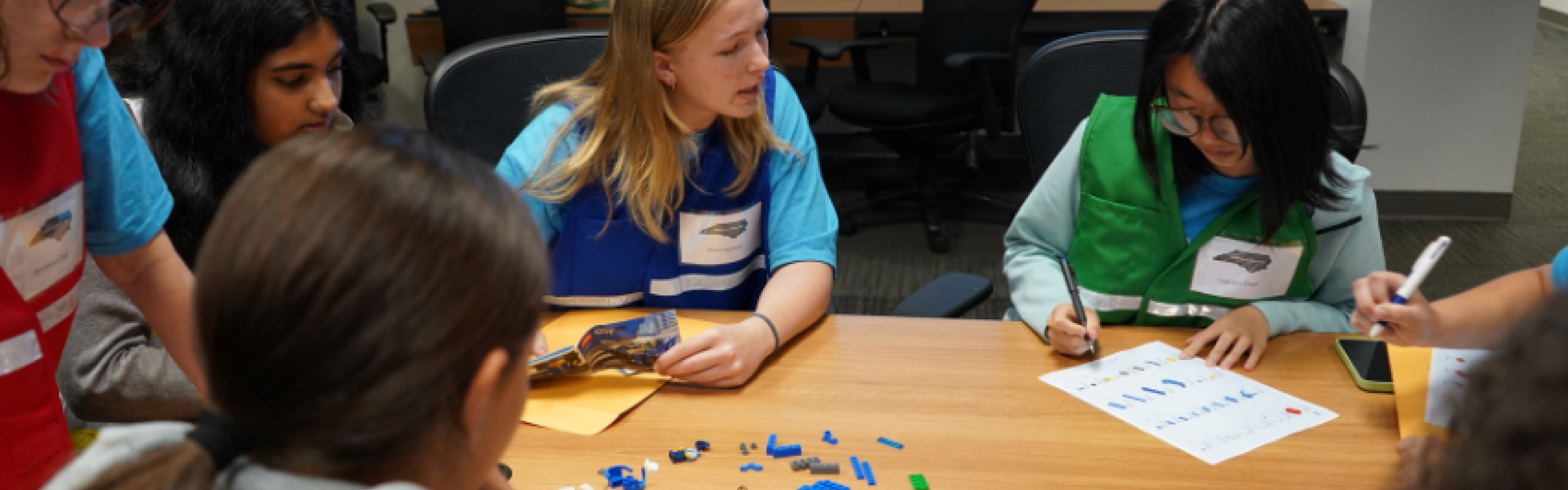 A group of young women gathered around a table playing a game. 